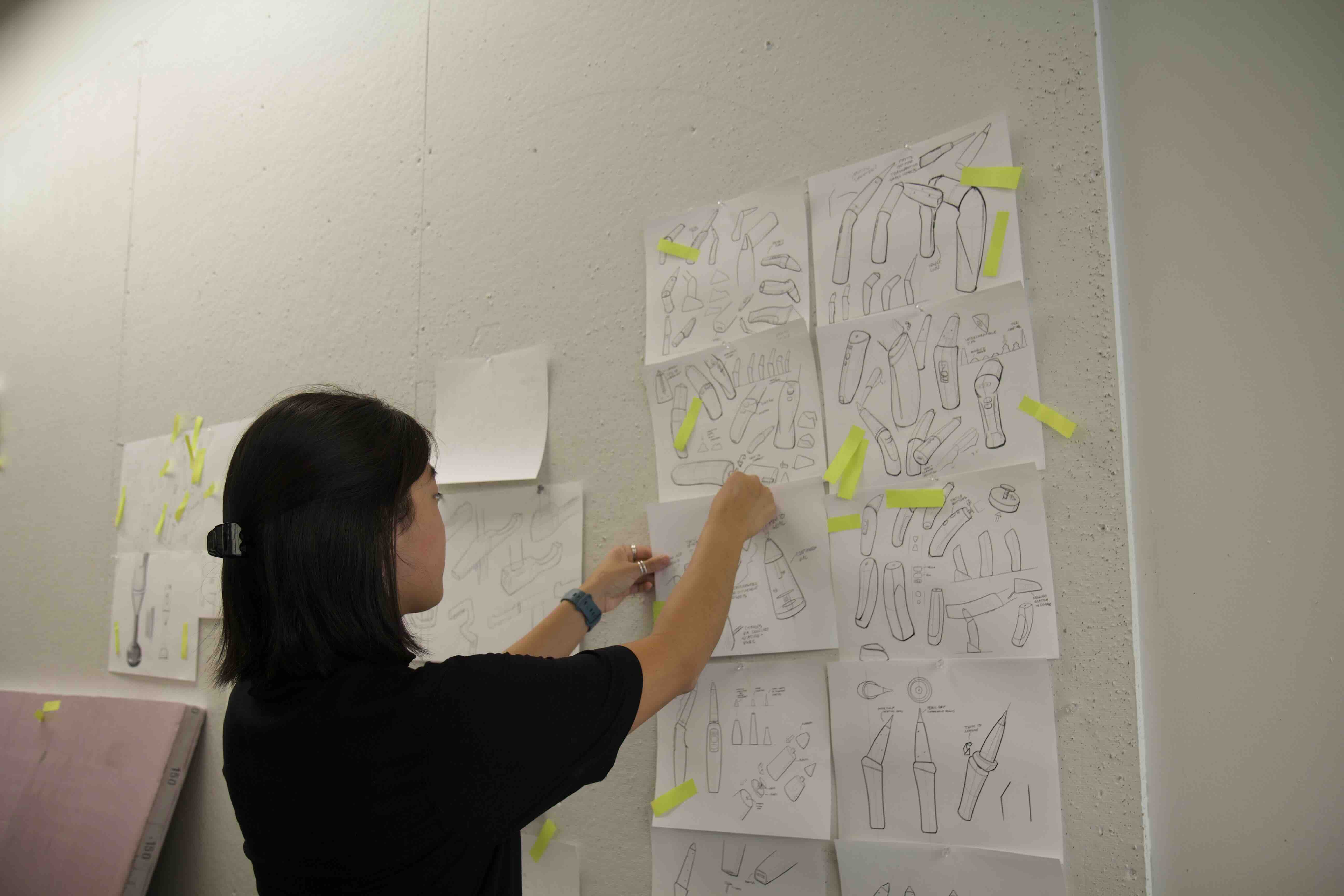 Zoe pinning papers on the board.