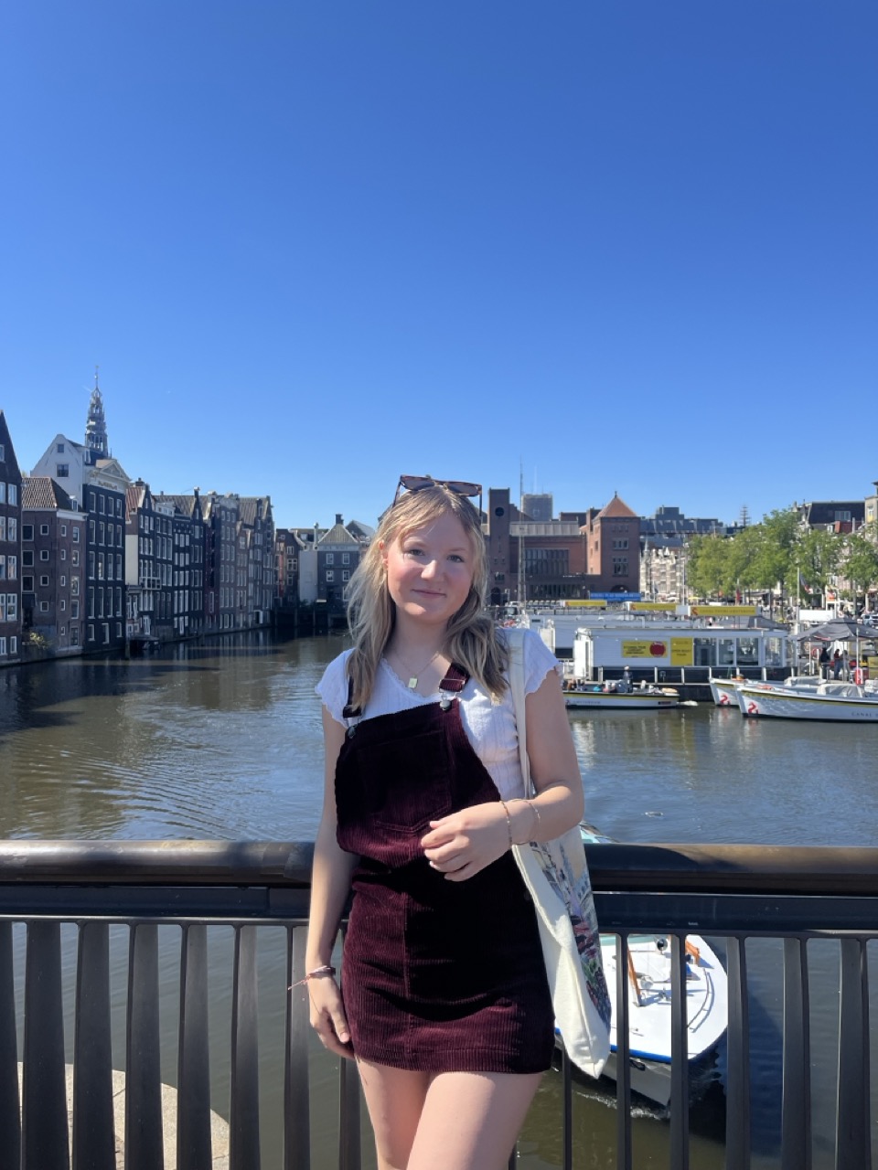Girl with blonde hair standing on a bridge that overlook a canal in Amsterdam 