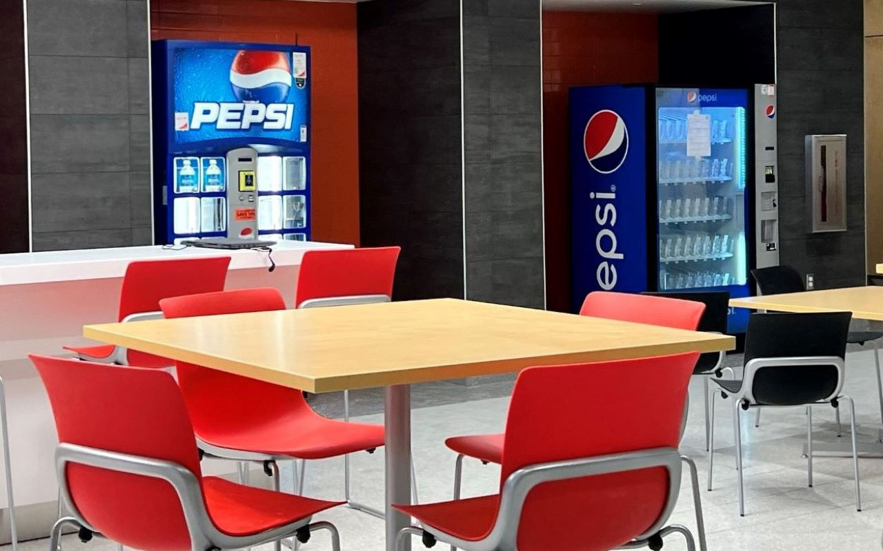 Table and chairs in common kitchen with vending machines