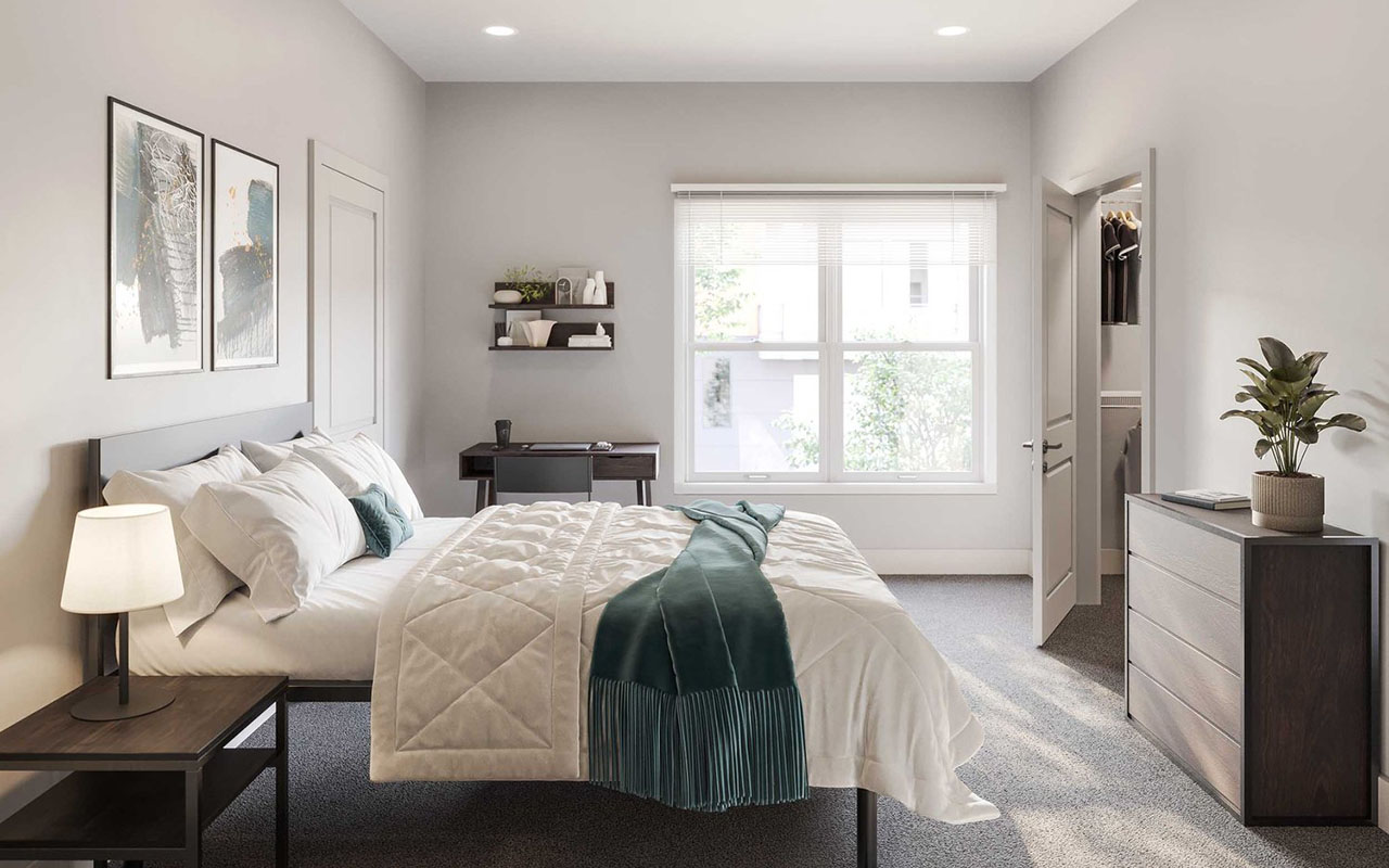 Brightly lit bedroom with bed, desk, nightstand, dresser and closet.