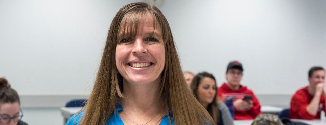 UC Clermont Professor Patty Goedl smiles in front of a classroom of students.