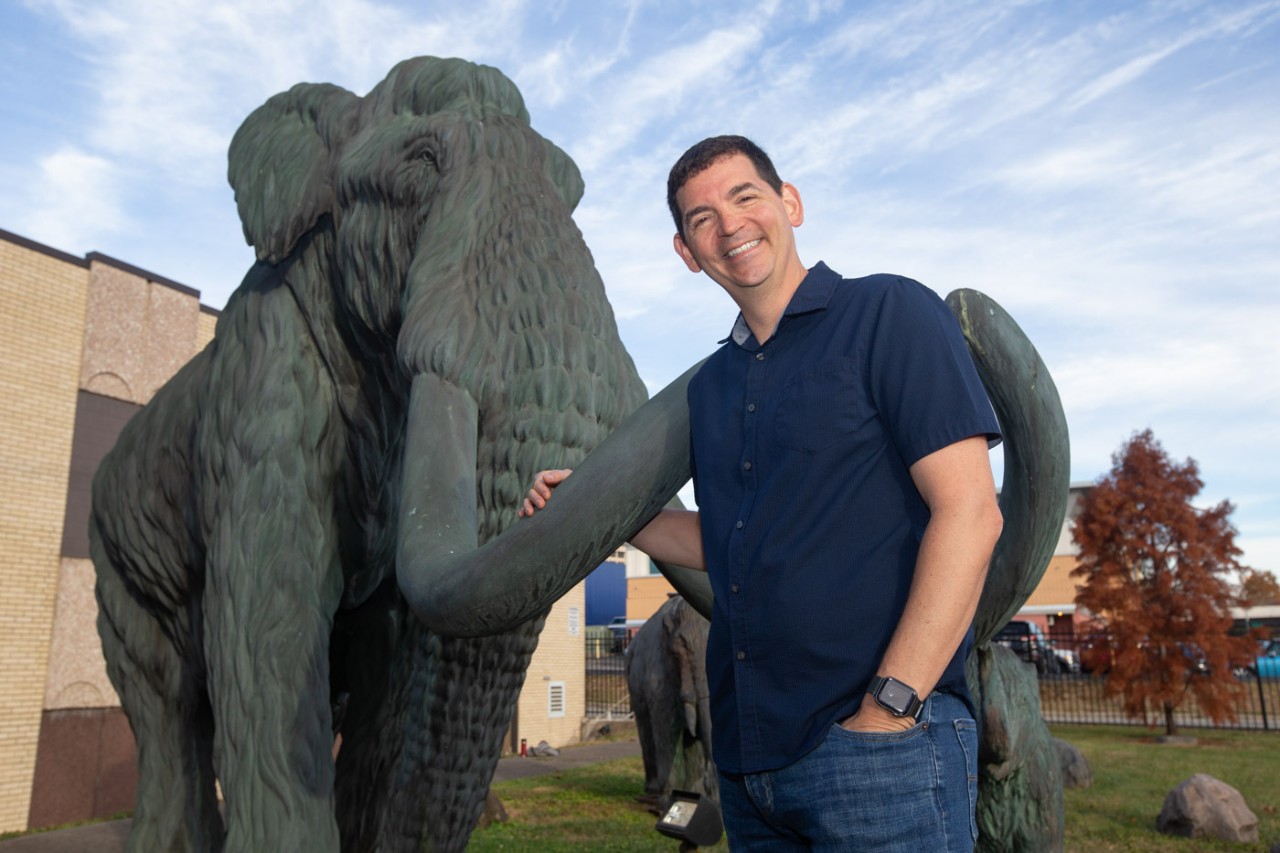 Joshua Miller stands in front of a bronze mammoth outside the Geier Collections and Research Center.