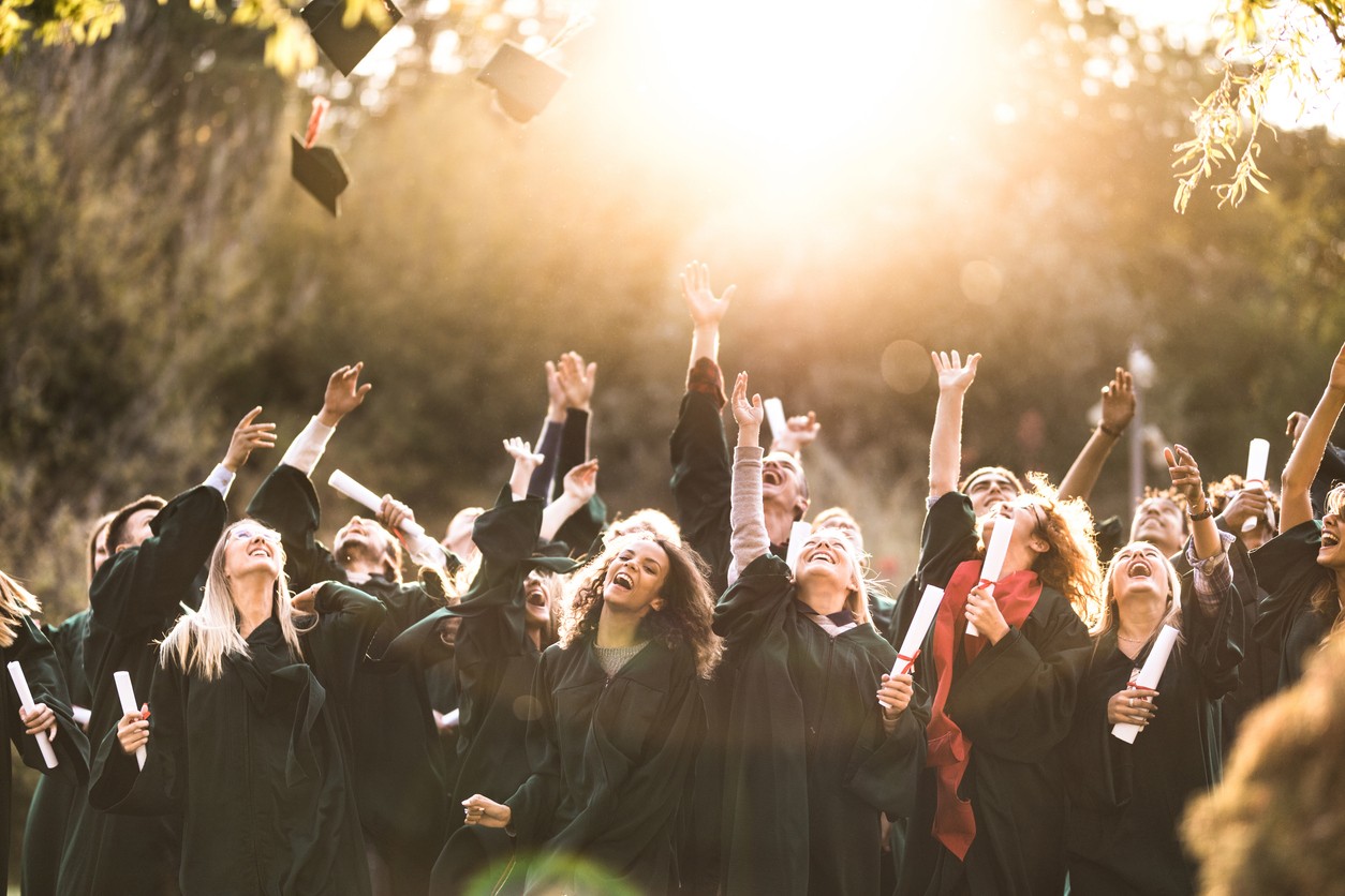 Group of happy graduates, throwinng their caps into the air.