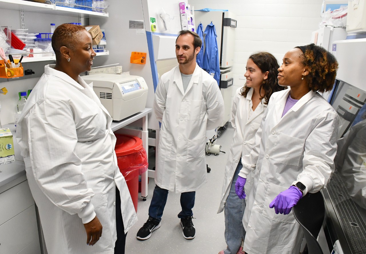 Four people in labcoats confer in a biomedical engineering lab.