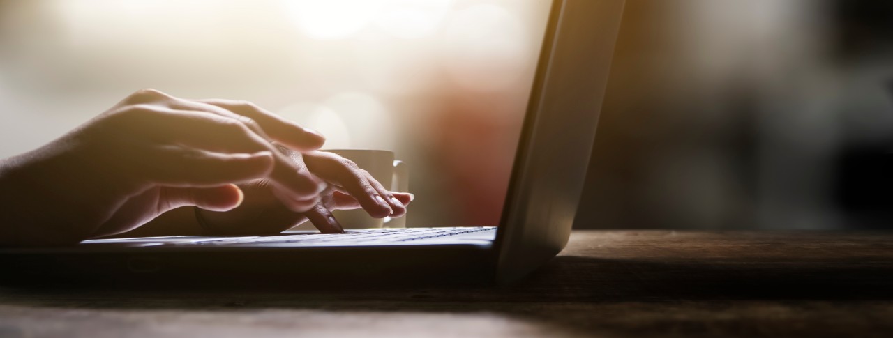 Hands on a laptop keyboard, writing an email to a professor