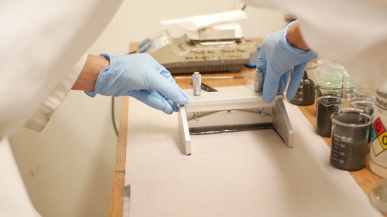 Nichols runs a casting knife across the surface of a graphene catalyst slurry.