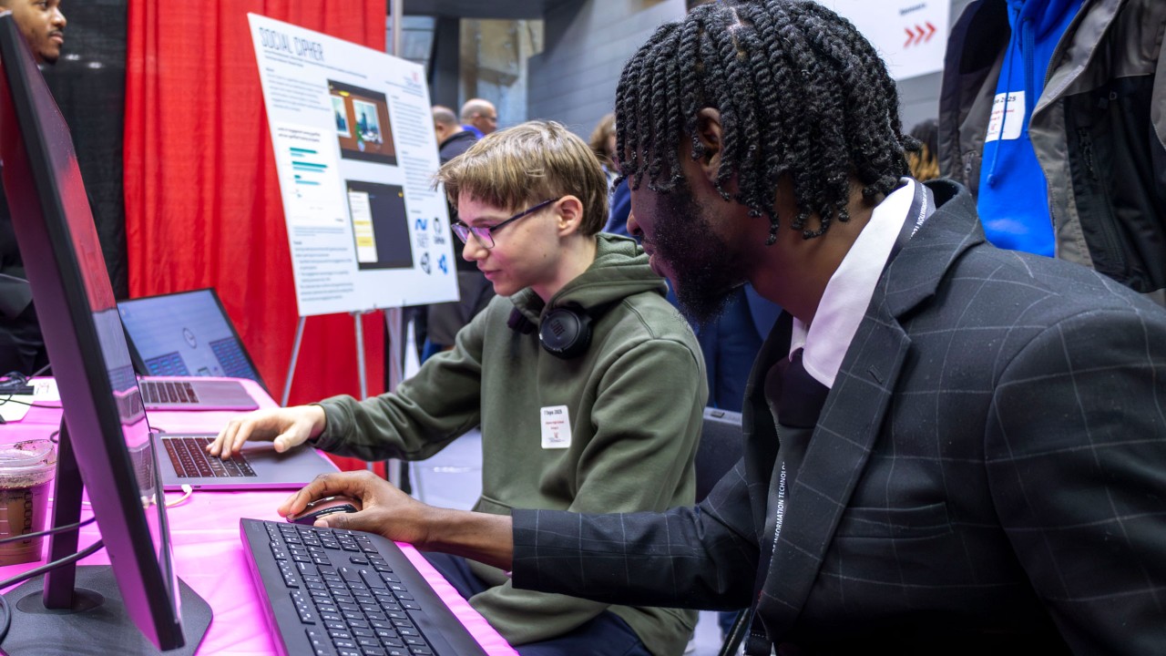 two students at laptops at an event