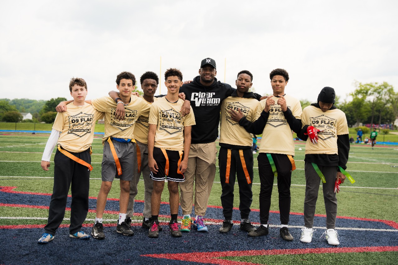 NFL player, Mack Wilson of the Arizona Cardinals stands with young flag football athletes.